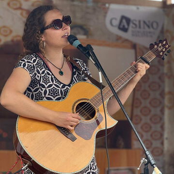 Sängerin mit Sonnenbrille spielt Akustikgitarre, secret stage, Kieler Woche 2025