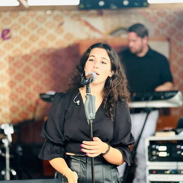 Sängerin in Schwarz am Mikrofon, dahinter ein Keyboarder, secret stage, Kieler Woche 2025