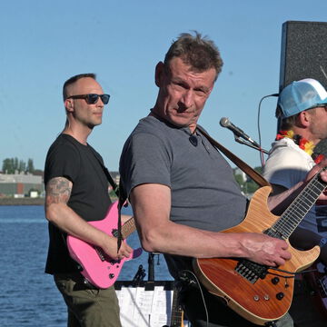 Gitarristen mit Sonnenbrillen spielen vor blauem Himmel an der Förde, secret stage, Kieler Woche 2026