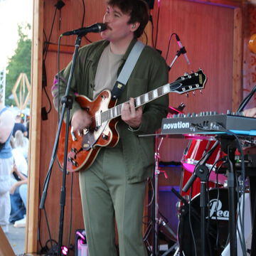 Gitarrist im grünen Anzug am Mikrofon, secret stage, Kieler Woche 2023