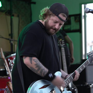 Tätowierter Gitarrist mit Basecap und Bart an der E-Gitarre, secret stage, Kieler Woche 2026