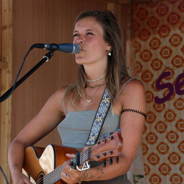 Sängerin mit Akustikgitarre singt ins Mikrofon, secret stage, Kieler Woche 2023