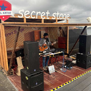 Musiker mit Hut, Gitarre und Keyboard auf der secret stage mit Kiel Artist Schild, Kieler Woche 2025
