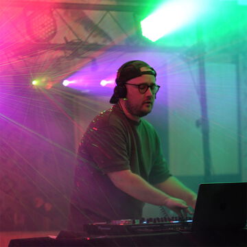 DJ mit Kopfhörern im bunten Lichtstrahl der Scheinwerfer auf der secret stage, Kieler Woche 2026