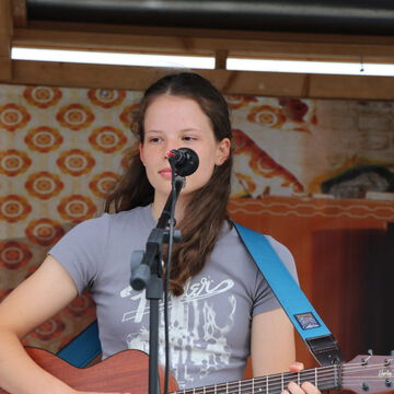 Junge Sängerin mit Gitarre am Mikrofon, secret stage, Kieler Woche 2023