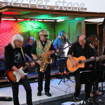 Band mit Gitarren und Saxofon im grün-roten Licht der secret stage, Kieler Woche 2024