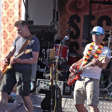 Zwei Gitarristen in Shorts, einer mit Blumenkette, auf der secret stage, Kieler Woche 2026
