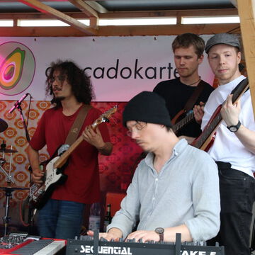 Band mit Gitarren und Keyboard vor dem avocadokartell Banner, secret stage, Kieler Woche 2023